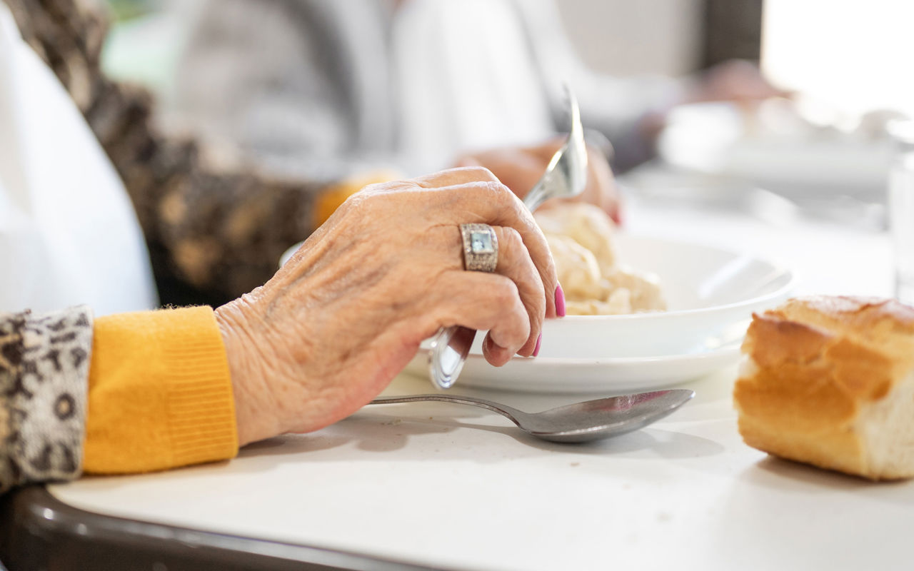 Hånd fra en ælde dame der spiser mad